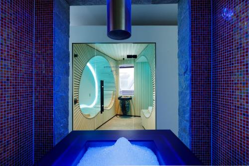a bathroom with a blue tub and a mirror at Hotel Belvoir Lake View & Spa in Rüschlikon