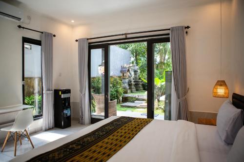 a bedroom with a bed and a large window at Parafrutts Apartments by Ateliero in Ubud