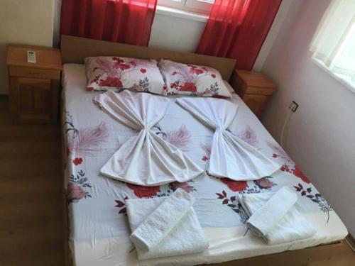 a bed in a small room with a white bedspread and pillows at Къща Йорданови in Chernomorets