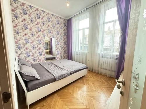 a bedroom with a bed with purple walls and windows at Apart 26 in Odesa