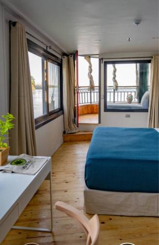 a bedroom with a bed and a table and windows at Dahabiya cruise in Luxor