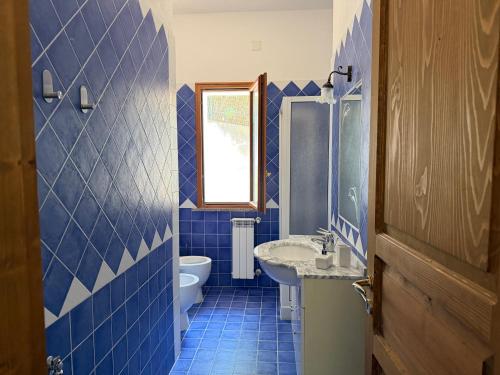 a blue tiled bathroom with a toilet and a sink at Marinella Retreat - Sole in Zambrone