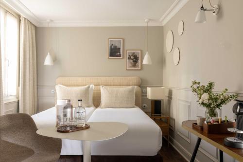 a bedroom with a white bed and a table at Hôtel Madeleine Haussmann in Paris