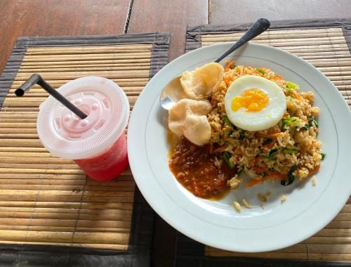 a plate of food with an egg and a drink at Batur Tropical in Kintamani