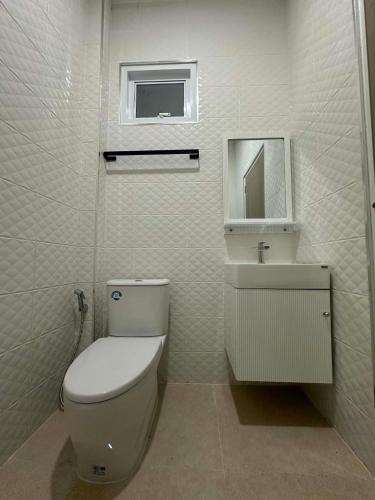 a white bathroom with a toilet and a sink at The Summer Cozy Cottage in Haad Chao Phao