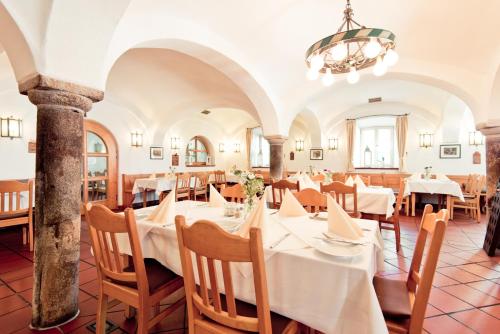 restauracja z białymi stołami i krzesłami oraz żyrandolem w obiekcie Schweiger's Landgasthof w mieście Wartenberg