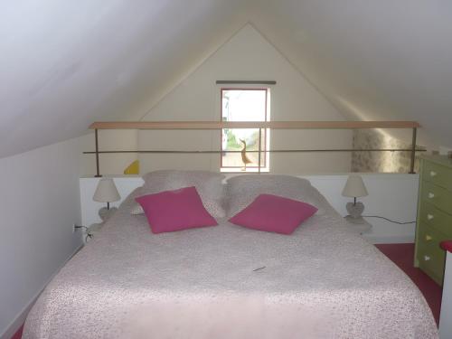 a bedroom with a large bed with two purple pillows at L'ânesque in Saint-Augustin-des-Bois