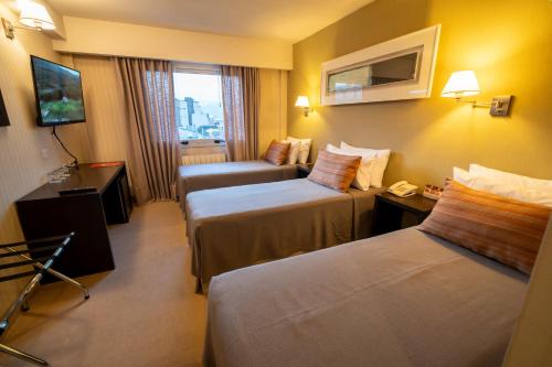 a hotel room with two beds and a couch at MIL810 Ushuaia Hotel in Ushuaia