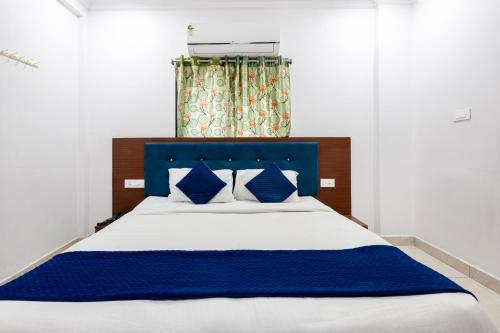 a bedroom with a blue and white bed with blue pillows at Hotel Aditya Premier in Guntūr