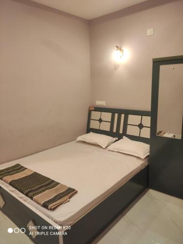 a small bedroom with a bed with white sheets at Sahyadri Lodge Yermala in Yermala