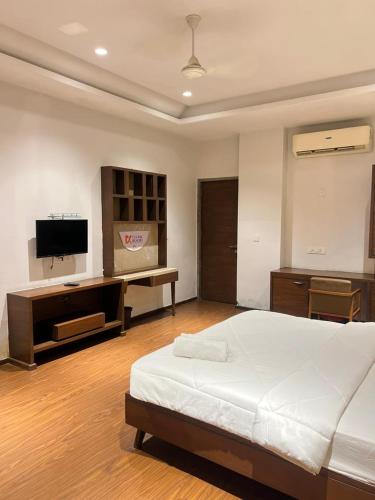 a bedroom with a bed and a desk and a television at DK Club & Resort in Bārdoli