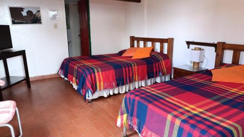 a room with two beds and a tv in it at Finca Hotel Caracolí I A 15 Minutos del Parque del Café in Montenegro
