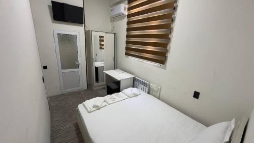 a small white room with a bed and a mirror at Sohil Hotel in Stantsiya Kyzyl-Tukumachi