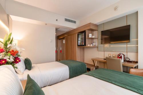a hotel room with two beds and a desk at Américas Copacabana Hotel in Rio de Janeiro