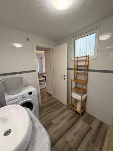 a bathroom with a sink and a washing machine at Apartmani Brač in Pučišća