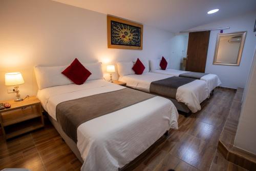 two beds in a hotel room with red pillows at Aguacatala Hotel Boutique in Medellín