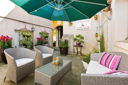 eine Terrasse mit Stühlen und einem Tisch mit einem Sonnenschirm in der Unterkunft La Pergola in Châteauneuf-du-Pape