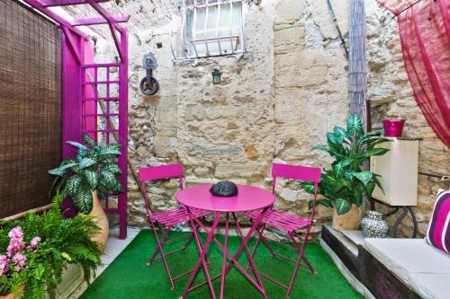 d'une terrasse avec une table rose et deux chaises. dans l'établissement La Pergola, à Châteauneuf-du-Pape