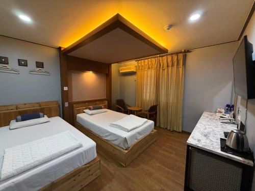 a hotel room with two beds and a table at Sweet Hotel in Jeju