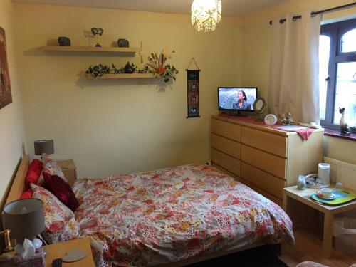 a bedroom with a bed and a dresser and a television at The Cedars House B&B in Nuneaton
