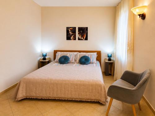 a bedroom with a bed with blue pillows and a chair at Casa Iris in Montepulciano