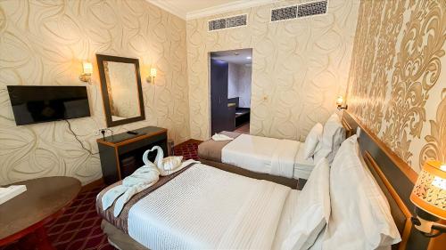 a hotel room with two beds and a mirror at Elite Jonrad Hotel LLC in Dubai