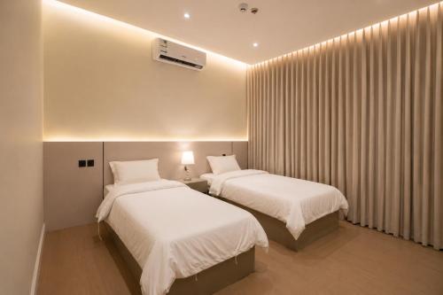 two beds in a hotel room with white sheets at فندق دواد الدوادمي Dewad Hotel in Ad Dawādimī