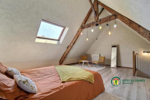 a attic bedroom with a bed and a table at La grée des dinosaures in Saint-Gravé