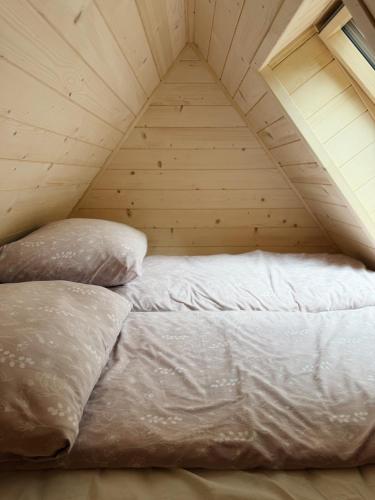 a bed with white sheets and pillows in a attic at Tiny nad potokiem - Leśny in Sidzina