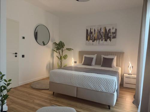 a white bedroom with a bed and a mirror at Sky Residence House in Cluj-Napoca