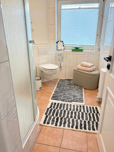 ein Badezimmer mit Dusche, Toilette und Teppich in der Unterkunft Syltfisch in Sylt