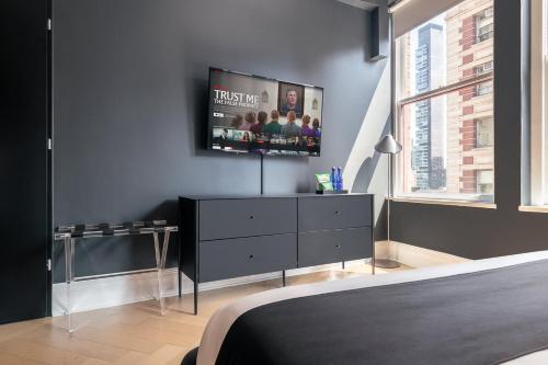 a bedroom with a dresser with a tv on the wall at Broadway Hotel in the Flatiron District in New York