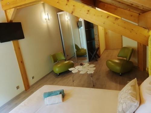 a bedroom with a bed and green chairs and a table at Compagnie des gites de luxe in Gérardmer
