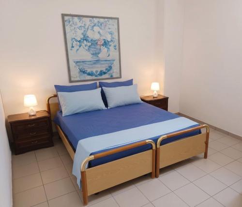 a bedroom with a bed with blue sheets and two lamps at SteLuRe in Aradeo