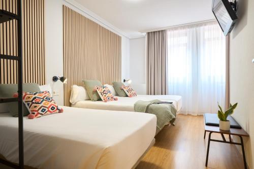 a hotel room with two beds and a couch at Hotel Centro Vitoria AutoCheckIn in Vitoria-Gasteiz