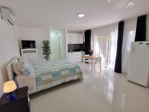 a bedroom with a bed and a kitchen with a refrigerator at AVENTURA STUDIOS with TROPICAL POOL - playa LOS CORALES in Punta Cana
