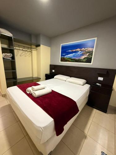 a bedroom with a large white bed with a red blanket at Apartamentos La Posta in San Salvador de Jujuy