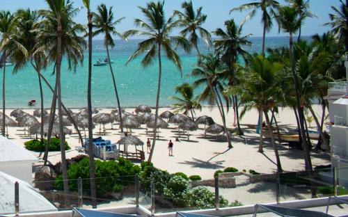 a view of a beach with palm trees and the ocean at AVENTURA STUDIOS with TROPICAL POOL - playa LOS CORALES in Punta Cana