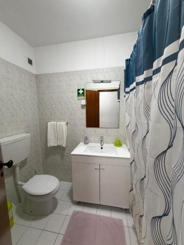 a bathroom with a sink and a toilet and a mirror at Casa Caravela B in Armação de Pêra
