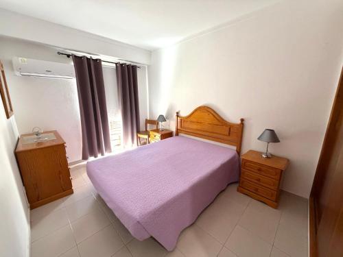 a bedroom with a bed with a purple blanket at Casa Caravela B in Armação de Pêra