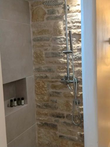 a shower in a bathroom with a stone wall at Liodentro House in Karpathos