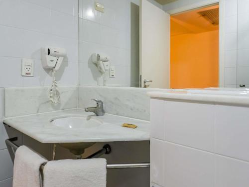 a white bathroom with a sink and a phone at ibis Guarulhos Aeroporto in Guarulhos