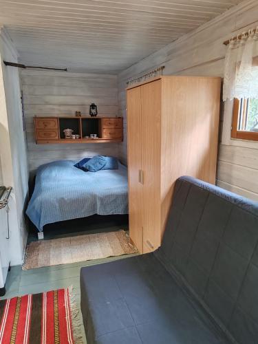 a small bedroom with a bed and a cabinet at Metsämökki in Lohja