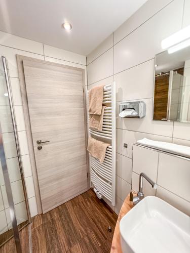 a bathroom with a shower and a sink and a door at Landgasthof Mörsbergei in Bubenreuth