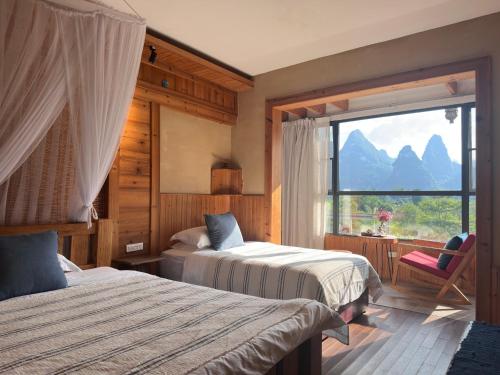a bedroom with two beds and a large window at Yangshuo Shui Mo Ju courtyard-Yangshuo Raiway St'ation free pick up for two nights in Yangshuo