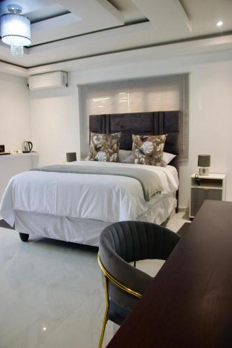 a bedroom with a large bed with a table and a chair at Kumnandi Guesthouse in Beacon Bay