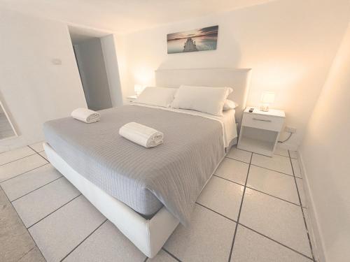 a white bedroom with a bed with towels on it at The Six Ortigia Residences in Syracuse