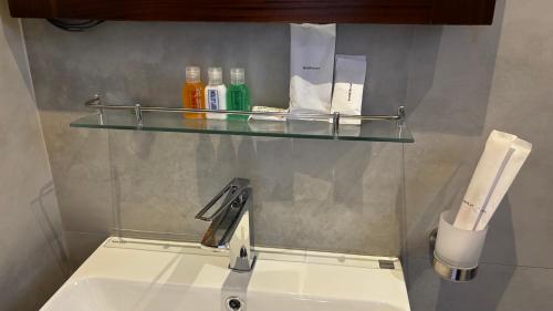 a bathroom sink with a glass shelf above it at Paris Garden Resort in Trincomalee