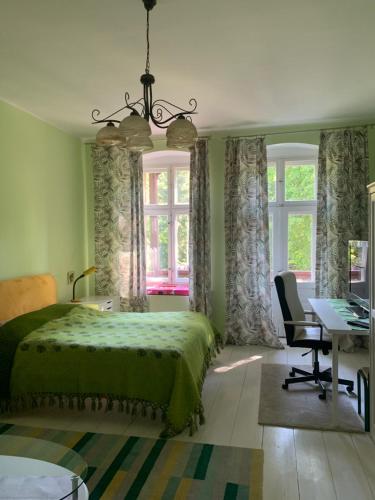 a bedroom with a green bed and a desk and windows at Villa Maria Rosaria in Oborniki Śląskie