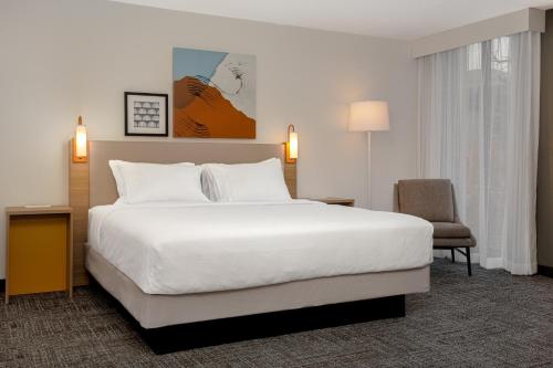 a hotel room with a large bed and a chair at Spark by Hilton Edmundston in Edmundston